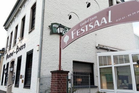 Seitenansicht des hell angestrichenen Hauptgebäudes mit Schriftzug Festsaal über den Nebeneingang