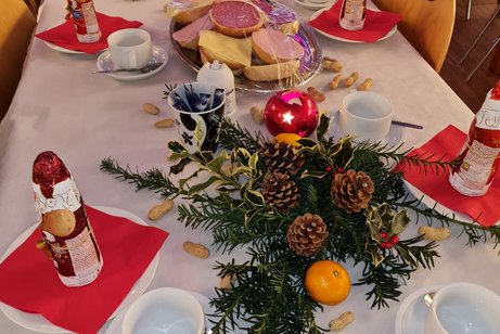 Weihnachtliche eingedeckter Tisch mit Schokoladennikolaus, belegten Brötchen und Tannengesteck