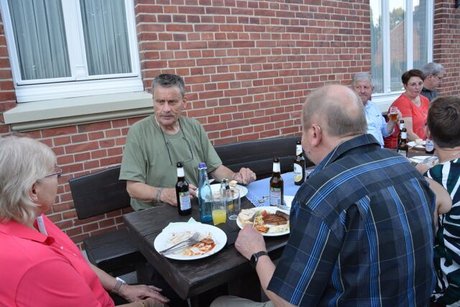 Menschen sitzen vor Haus Hoppe an einem Holztisch und essen.