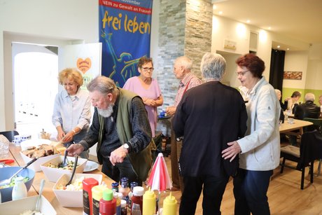 Mitglieder vom Ortsverband. Mehrere Personen stehen im Raum und unterhalten sich miteinander.