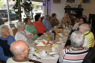 Viele Menschen sitzen gemeinsam beim Frühstück an einem langen Tisch.