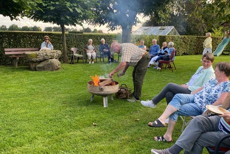 Mitglieder sitzen gemütlich um eine Feuerschale