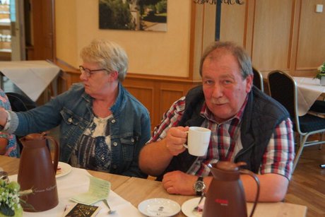 Eine Frau und ein Mann sitzen bei Kaffee und Kuchen an einem Tisch.