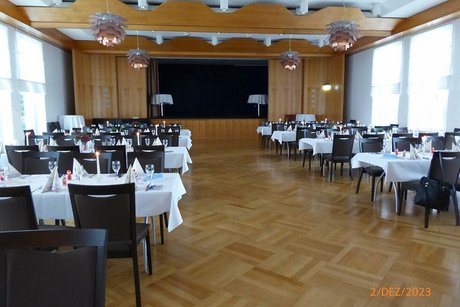 Menschenleerer Saal mit weihnachtlich geschmückten Tischen
