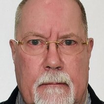 Portrait eines Mannes mit dunkelblondem Kurzhaarschnitt und Brille, der lächelt