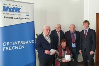 Vier Männer und eine Frau haben sich neben einem Roll-Up mit VdK-Logo und Schriftzug Ortsverband Frechen zu einem Gruppenfoto platziert.