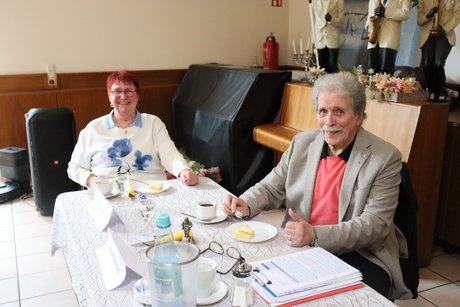 Eine Frau und ein Mann sitzen an einem Tisch mit Kaffee und Kuchen.