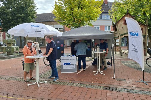 Marktstand in Borghorst Marktstand in Borghorst, mit Sonnenschirm und Zeltpavillon. Am Stehtisch steht Herr Meiers und unterhält sich mit einem Gast.