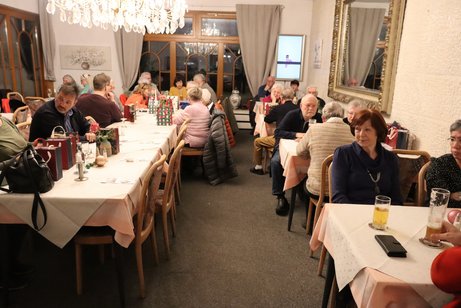 Mehrere Menschen sitzen an gedeckten Tischen.