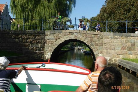 Das Ausflugsboot steuert auf eine steinerne Bogenbrücke zu.