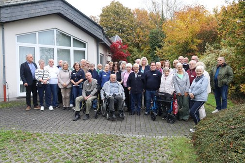 Mehrere Menschen stehen für ein Gruppenbild draußen vor dem Haus zusammen.