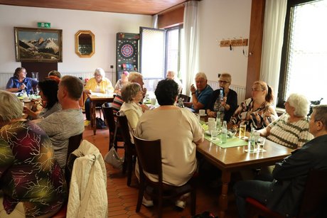 Mehrere Personen sitzen an gedeckten Tischen und unterhalten sich.