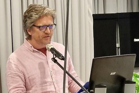 Ein Mann steht an einem Rednerpult mit Mikrofon