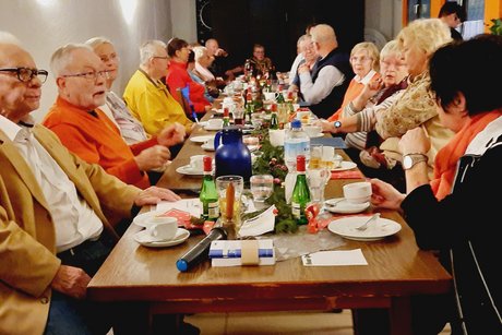 Menschen sitzen an einem langen und festlich gedecktem Tisch.