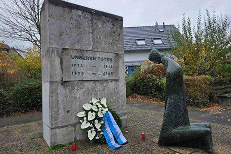 knieende Frau vor Ehrenmal mit Kranz des VdK