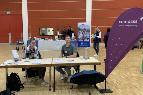 Das Bild zeigt zwei Vertreter einer Privaten Pflegeberatung am Messestand