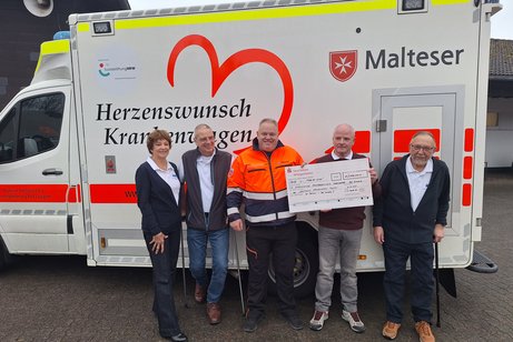 Einige Vorstandsmitglieder des VdK-Ortsverbandes stehen gemeinsam mit Michael Hermann bei der Spenden&uuml;bergabe vor dem Herzenswunsch-Krankenwagen der Malteser
