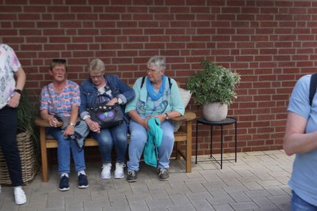 Drei Frauen sitzen nebeneinander auf einer Holzbank