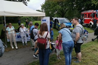 Menschen am VdK-Infostand. Im Hintergrund schauen sich Kinder ein Polizeiauto und ein Feuerwehrauto an.