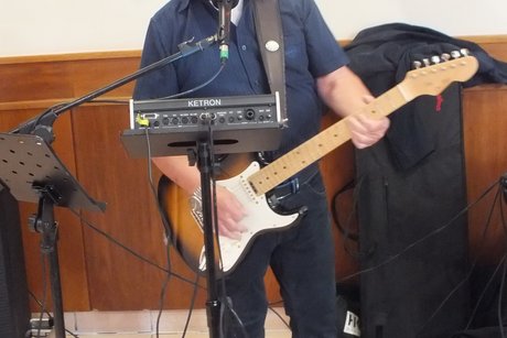 Ein Musiker mit Gitarre singt etwas in ein Mikrophone.