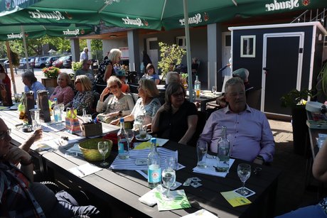 Mehrere Menschen sitzen im Biergarten an Tischen.