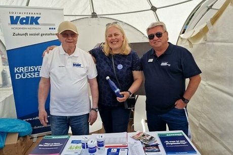 Drei Menschen stehen gemeinsam am Messestand des VdK Düsseldorf