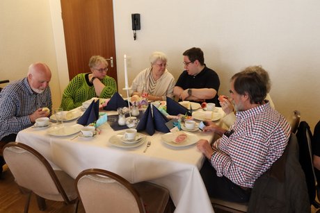 Mehrere Personen sitzen an einem gedeckten Tisch.