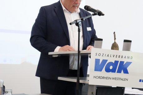 Ein Mann steht am Rednerpult und spricht zu den Delegierten.