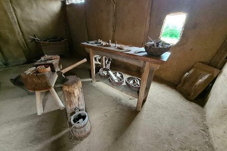 Blick in die nachgebaute Werkstatt eines Wikingers mit Holzbank und verschiedenen Weidenkörbchen mit Gerätschaften.