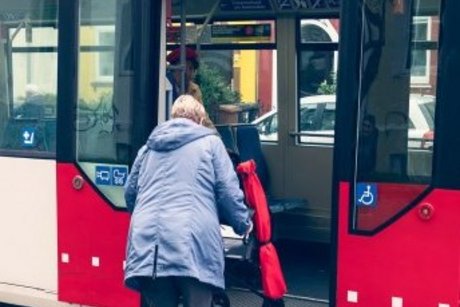 Frau schiebt Rollstuhl über eine Rampe im die Straßenbahn