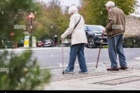 Gehbehinderte Senioren &uuml;berqueren eine Strasse