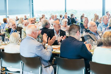 Viele Menschen sitzen an festlich gedeckten Tischen.