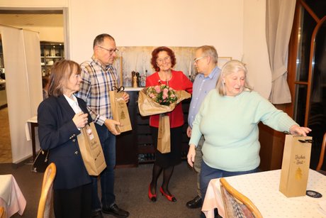 F&uuml;nf Personen stehen zusammen und eine Person &uuml;bergibt kleine Pr&auml;sente.