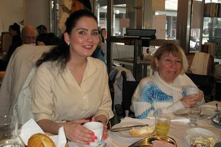 Zwei Frauen sitzen nebeneinander beim Frühstücken an einem Tisch.