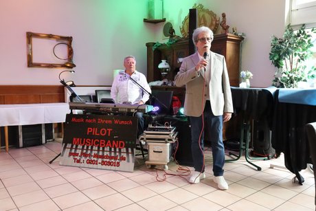 Frühlingsfest Ein Mann steht hinter einem Mischpult um Musik zu spielen und ein anderer Man steht an einem Mikrophone und begrüßt die Teilnehmer.