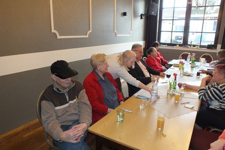 Mehrere Menschen sitzen an einem langen Tisch und spielen Bingo.