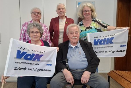 Zu sehen ist der neue VdK Vorstand im Kreisverband Mülheim an der Ruhr. Der neue Kassierer Ernst Osterhage fehlt aus gesundheitlichen Gründen. Die Personen halten 2 VdK Fahnen hoch.