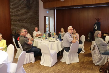 Mehrere Personen sitzen an einem runden Tisch.