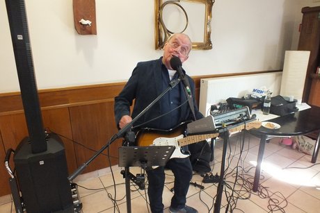 Ein Musiker mit Gitarre singt in ein Mikrophon.