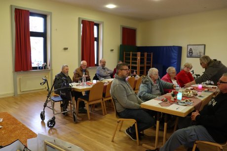 Mitglieder sitzen an gedeckten Tischen.