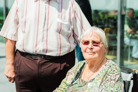 Eine Frau im Rollstuhl und daneben ein Mann.
