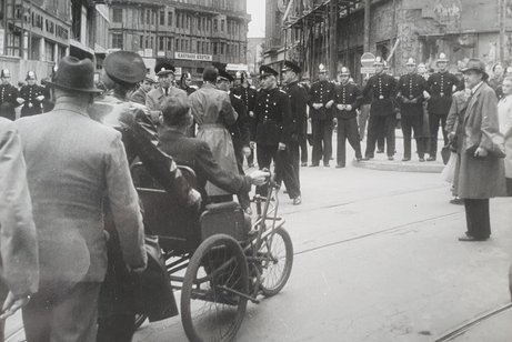Archivbild in Schwarz-Wei&szlig;. Kriegsversehrte in Rollst&uuml;hlen demonstrieren auf der Stra&szlig;e flankiert von uniformierten Schutzm&auml;nnern.