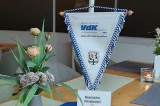 Blumenstrauß und blau-Weißer Wimpeldes Ortsverbands Dellbrück auf einem Restaurant-Tisch