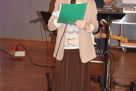 Eine Frau liest etwas von einem Zettel vor.