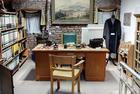 Ein Schreibtisch mit Stuhl, Robe, Gem&auml;lde und Aktenschrank