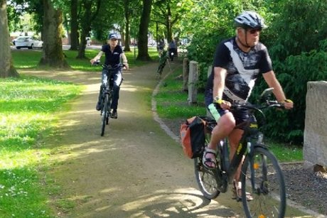 Zwei Radfahrer fahren durch eine Gr&uuml;nanlage
