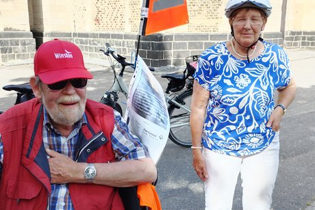 Mann sitzt auf Therapierad, Frau steht daneben.