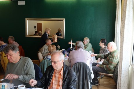 Mehrere Menschen sitzen an gedeckten Tischen.