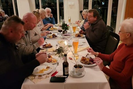 Menschen sitzen gemeinsam an einem langen Tisch beim Essen.
