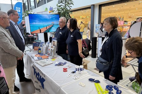 Drei Personen stehen hinter einem Informationsstand.